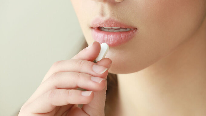 Beautiful young woman taking pill, closeup Antibiotika