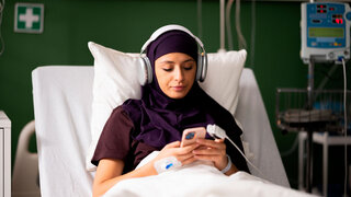 Frau im Krankenhaus hört Musik über Kopfhörer