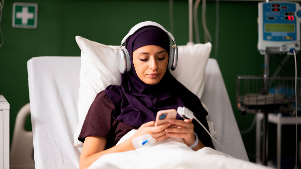 Frau im Krankenhaus hört Musik über Kopfhörer