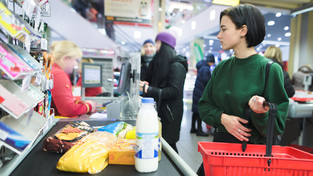 A beautiful girl stands at the supermarket and waits for a queue. The amount pays for purchases at the supermarket's cash desk. A beautiful girl stands at the supermarket and waits for a queue. The amount pays for purchases at the supermarket's cash desk
