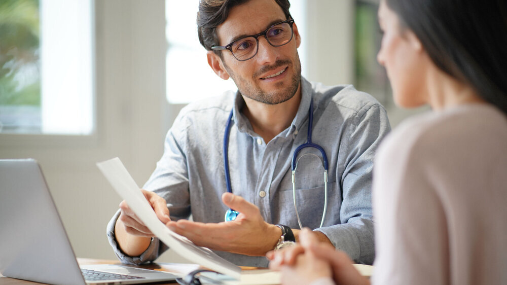 Modern young doctor speaking to patient in office junger Arzt