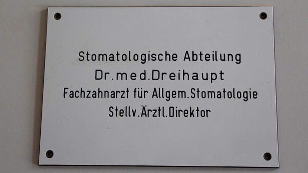 Das Türschild an der Poliklinik: „Ich hatte immer den Wunsch, Zahnarzt oder Tierarzt zu werden. Mein Vater empfahl mir, einen Beruf zu suchen, bei dem Staat und Regierung nicht hineinreden können. Das war in der Medizin noch gut möglich.“