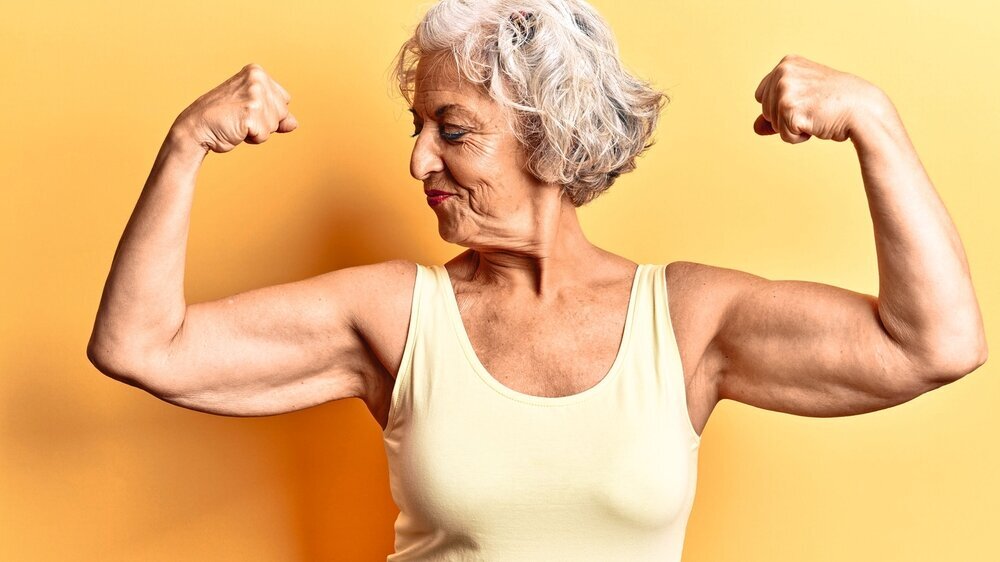 Senior grauhaarige Frau trägt legere Kleidung zeigt Arme Muskeln lächelnd stolz. Fitness-Konzept. Senior grauhaarige Frau trägt legere Kleidung zeigt Arme Muskeln lächelnd stolz. Fitness-Konzept.