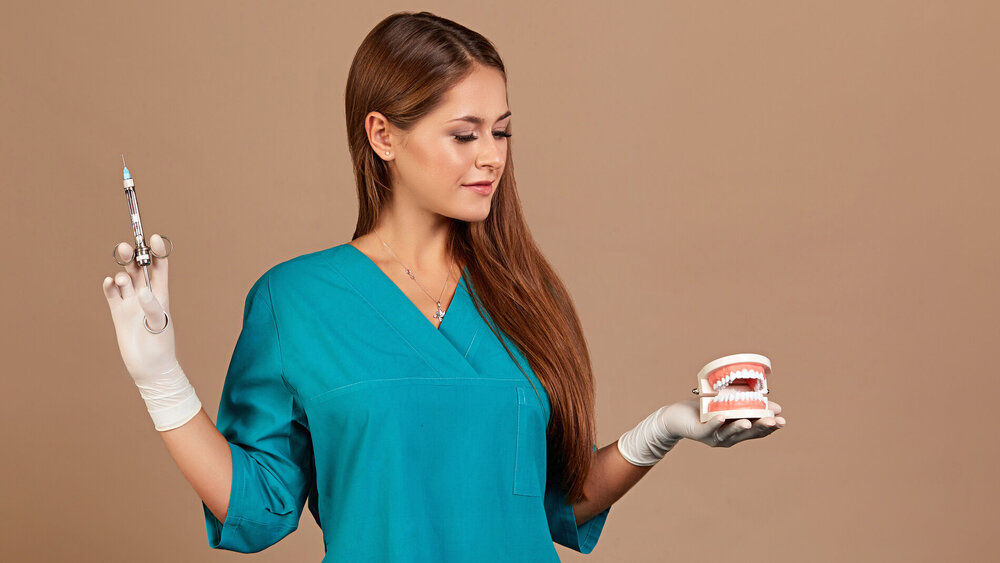 Junge zahnmedizinische Fachangestellte in der Ausbilung hält ein Gebissmodell in der Hand.