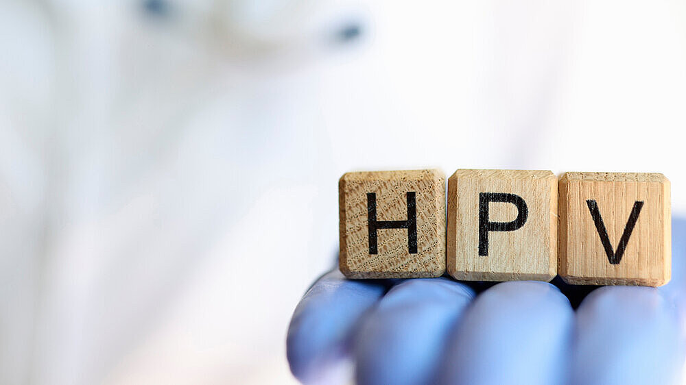 Female practitioner hand holding wooden cubes with word hpv Close-up of female practitioner hand holding wooden cubes with word hpv. Medicine and human papillomavirus acronym concept