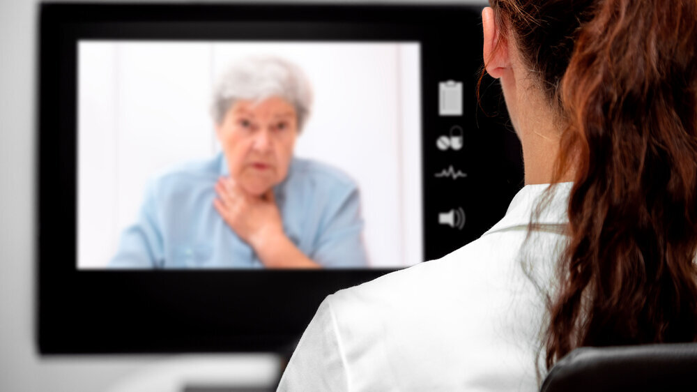 Kranke Patientin in der virtuellen Sprechstunde am Monitor, Fernbehandlung und Telematik im Gesundheitswesen