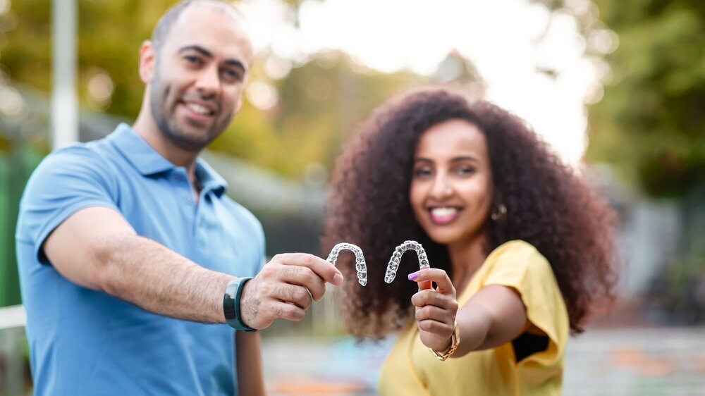 Handsome man with warm smiling is holding an invisaligner. Includes copy and text space.