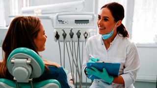 European mid dentist woman smiling while working with patient in dental clinic