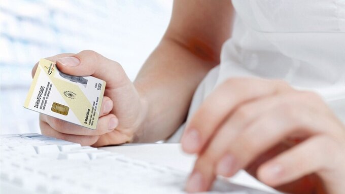 Junge Frau hält elektronischen Zahnarztausweis (eHBA)