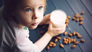 Kleines Mädchen mit Milch und Mandeln
