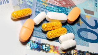 Tabletten und Kaspeln sind auf Euro-Geldscheinen platziert.