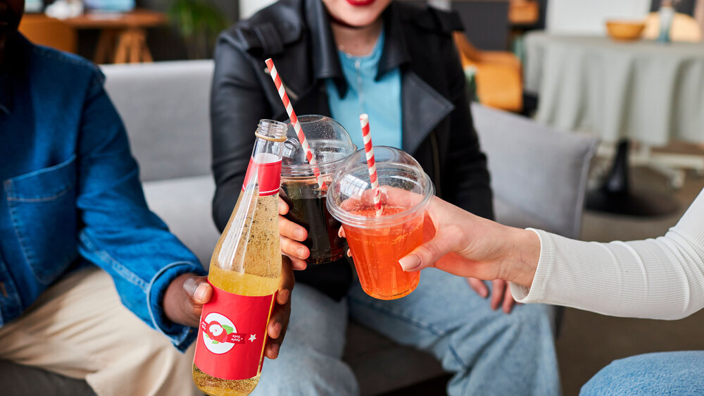 Nahaufnahme von einer Gruppe jungen Leuten, die Softdrins konsumieren und damit anstoßen.