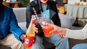 Nahaufnahme von einer Gruppe jungen Leuten, die Softdrins konsumieren und damit anstoßen.