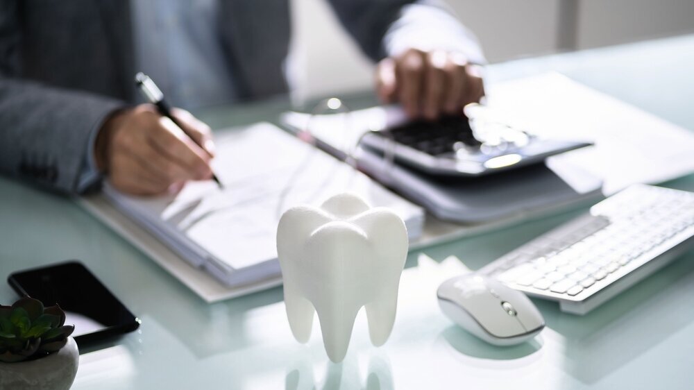 Close-up Of Tooth In Front Of Businessperson Calculating Bill