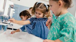 Kinder putzen sich die Zähne im Badezimmer eines Kindergartens