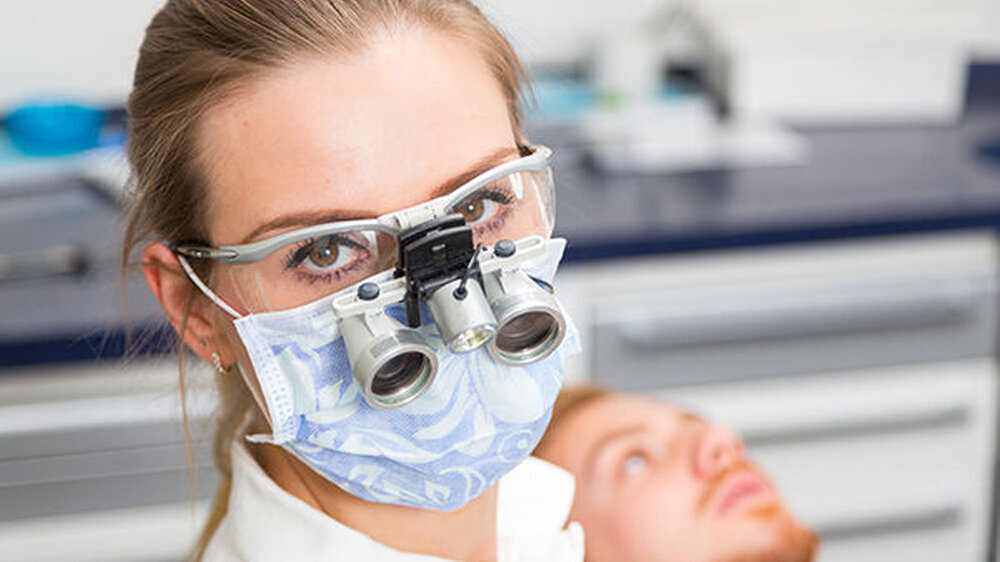 Eine ergonomische Sitzposition während der Patientenbehandlung kann berufsbedingten, chronischen Schmerzzuständen vorbeugen. Dentalhygenikerinnen hilft womöglich auch die Verwendung von Lupenbrillen.