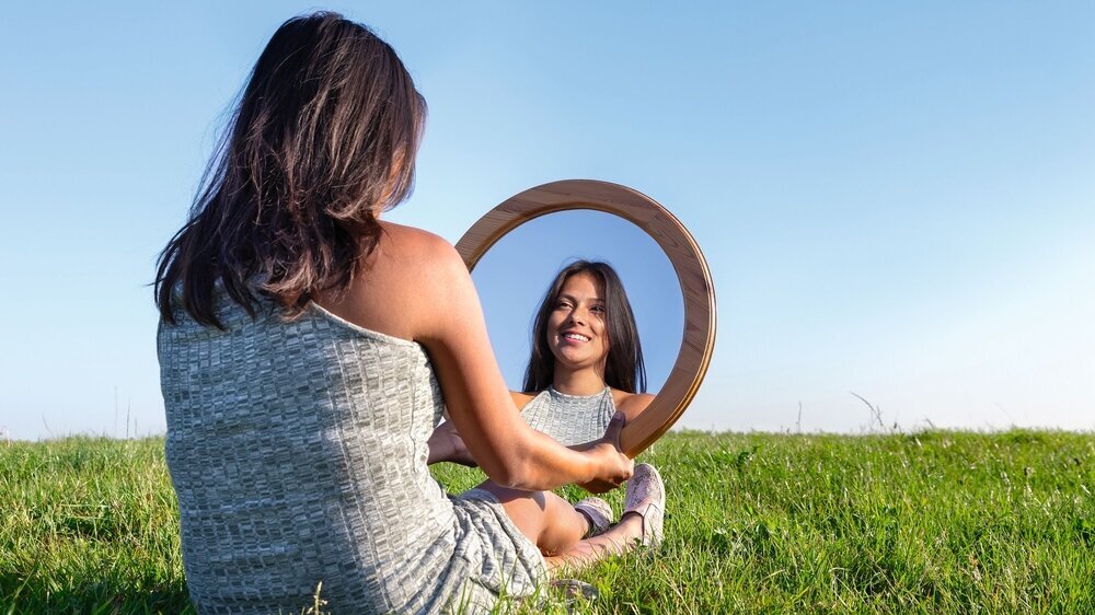 Woman in nature viewing her mirror image Frau mit Spiegel