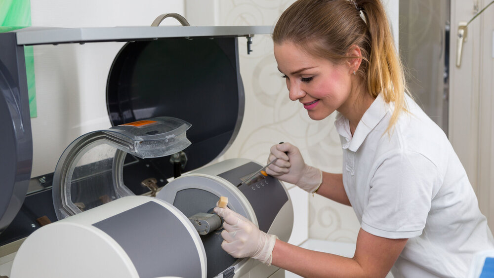 Dentist's assisstant operating CEREC Milling machine to produce dental implants