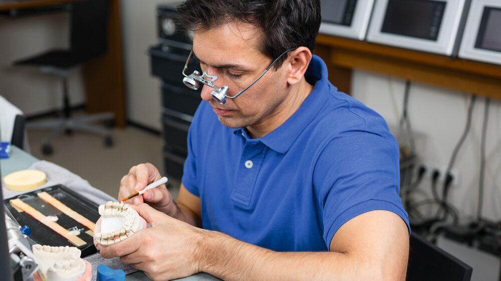 Dental lab technician appying porcelain to mold Zahntechniker
