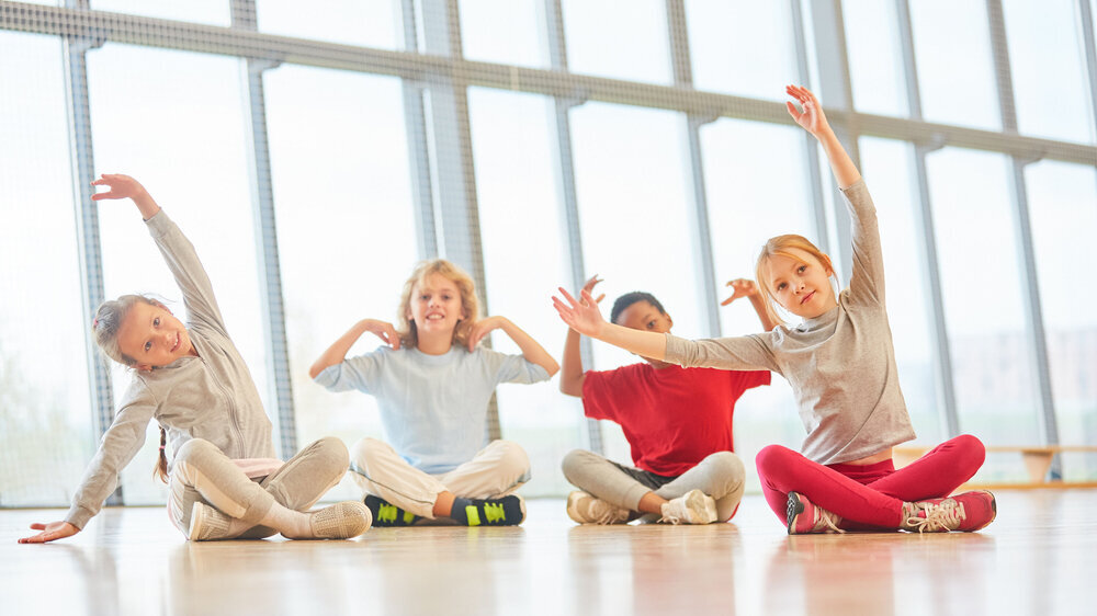Kinder beim Stretching im Sportunterricht Kinder beim Stretching im Sportunterricht