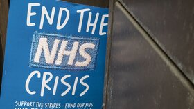 Ein NHS-Protestplakat von Krankenschwestern lehnt an einem Krankenhausgebäude.