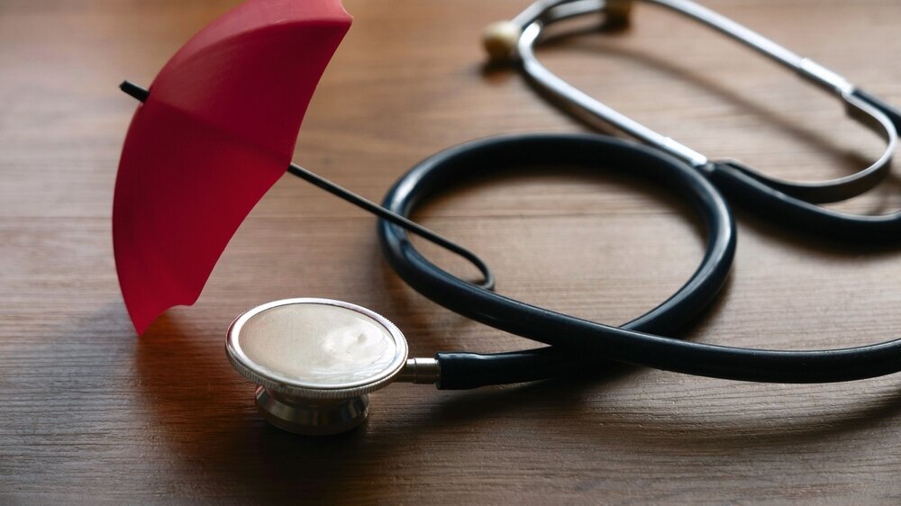 Health and insurance concept. Umbrella and stethoscope on wooden table.