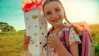 Mädchen bei der Einschulung mit bunter Schultüte im Arm.