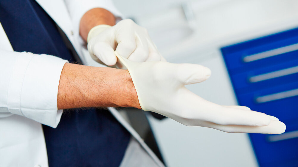 Zahnärztin zieht Schutzhandschuhe für die Operation an Zahnärztin zieht Schutzhandschuhe für die Operation an