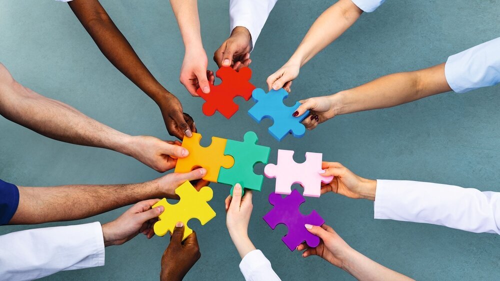 High Angle View Of Medical Team Solving Jigsaw Puzzle High Angle View Of Medical Team Solving Colorful Jigsaw Puzzle Against Grey Background
