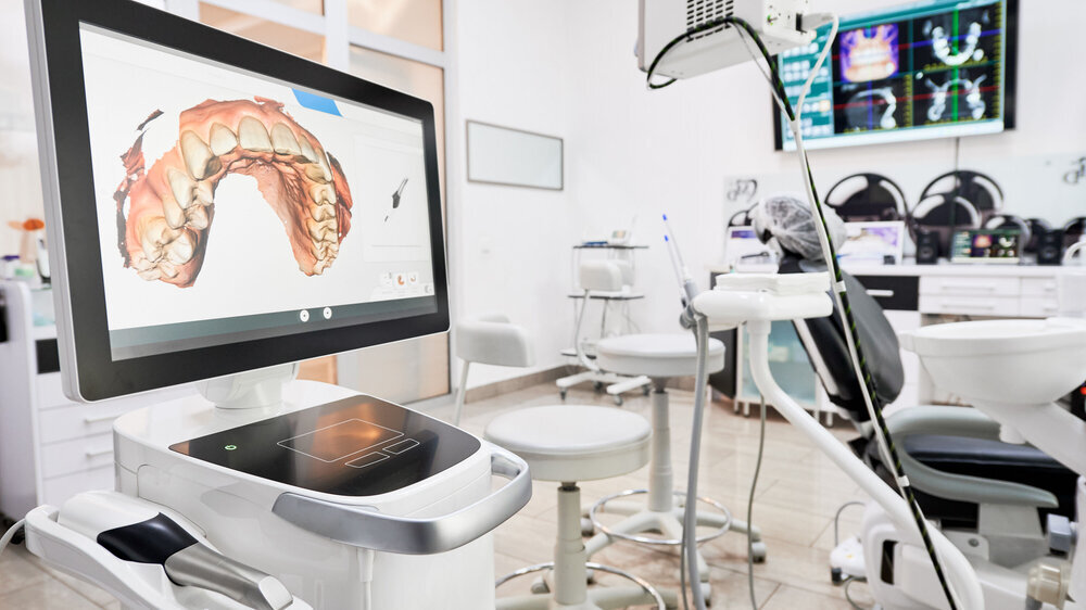 Innenraum einer Zahnarztpraxis mit moderner Ausrüstung und einem zahnärztlichen intraoralen Scanner mit Zähnen auf dem Display, medizinisches System für intraorales Scannen. Konzept der digitalen Zahnmedizin und der zahnmedizinischen Scantechnologie.