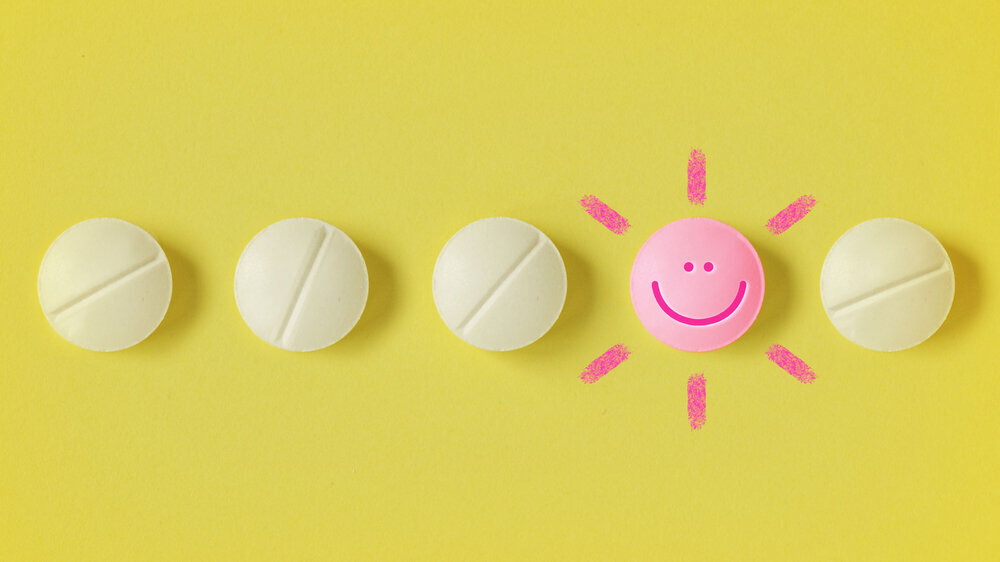 Pills in a row and pill with a happy face on yellow background - Concept of medicine, drug therapy and placebo effect Pills in a row and pill with a happy face on yellow background - Concept of medicine, drug therapy and placebo effect