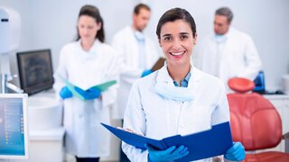 Smiling dentist holding file at dental clinic