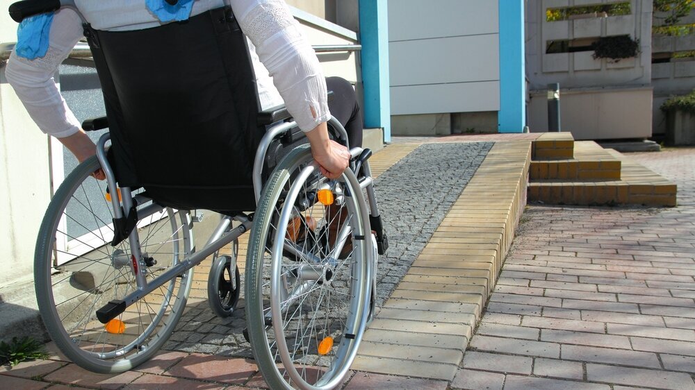 Frau im Rollstuhl auf Rollstuhlrampe Frau im Rollstuhl auf Rollstuhlrampe