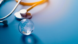 Globus und Stethoskop auf hellblauem Hintergrund,