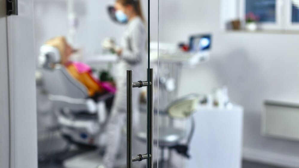Mouth checkup at the young dentist's office behind glass door ZÄ unscharf