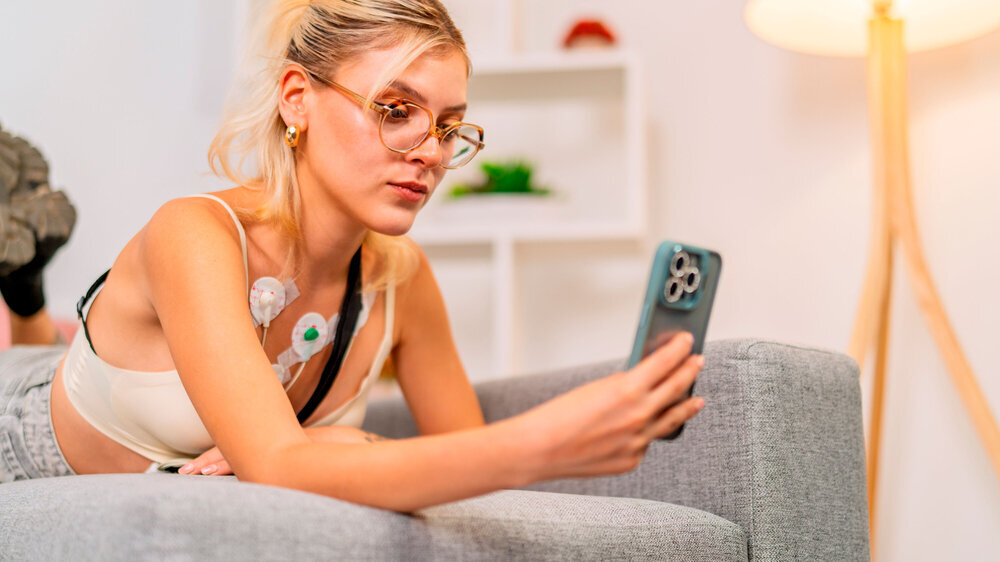 Junge Frau benutzt zu Hause ihr Smartphone für Gesundheitsfragen.