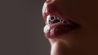 Nahaufnahme: Speichel tritt zwischen den Lippen hervor.