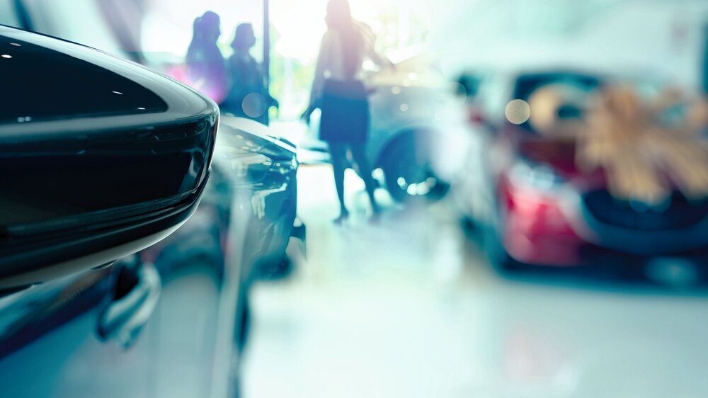 Selective side mirror car on blur saleswoman and customer in modern luxury showroom. Car dealership office concept. Dealer agent business. Automobile leasing service. Dealer company. New car purchase. Selective side mirror car on blur saleswoman and customer in modern luxury showroom. Car dealership office concept. Dealer agent business. Automobile leasing service. Dealer company. New car purchase.