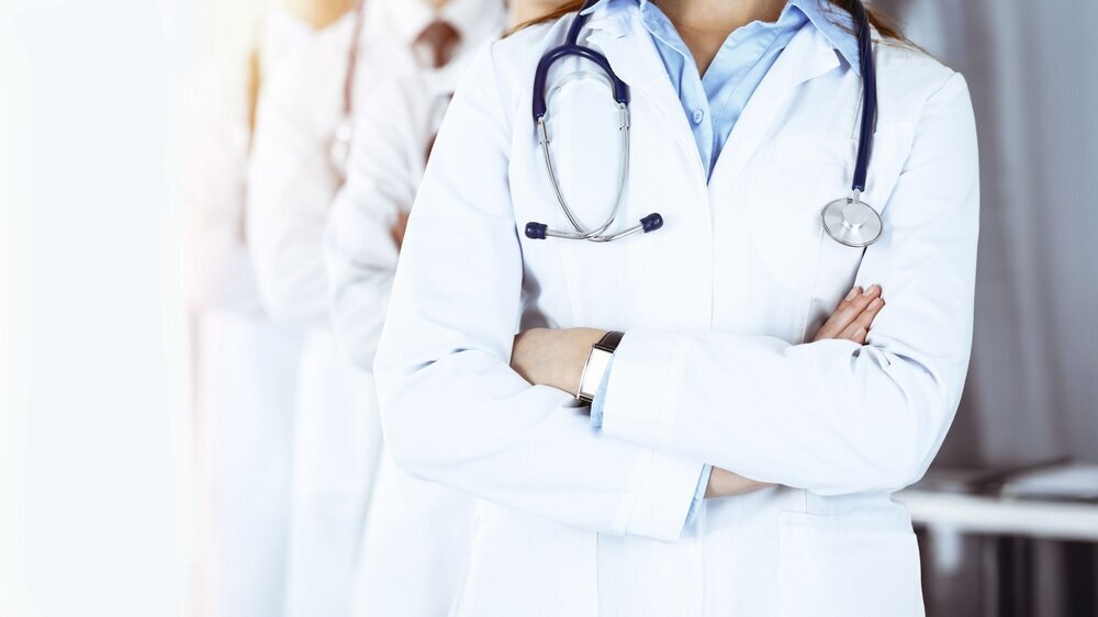 Group of modern doctors standing as a team with arms crossed in sunny hospital. Medical help, insurance in health care, best desease treatment and medicine concept.