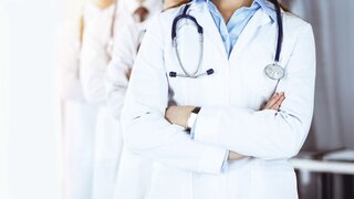 Group of modern doctors standing as a team with arms crossed in sunny hospital. Medical help, insurance in health care, best desease treatment and medicine concept.