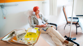 Eine Krebspatientin erhält eine Chemotherapie, zwei Infusionsbeutel liegen auf dem Tisch.