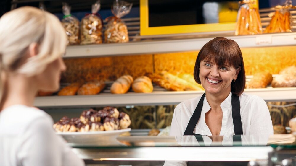Cheerful saleswoman is serving a customer in bakery Bäcker