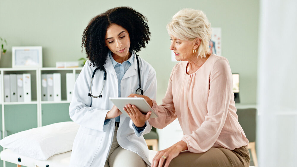 Ärztin mit Patientin und Tablet im Krankenhaus