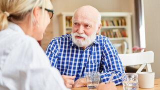 Senior Mann als Patient und Ärztin oder Pflegedienst Frau im Gespräch