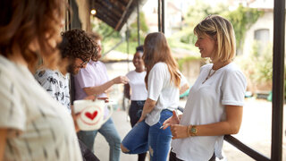 group of young adult people having a break at work, standing outdoor, smoking cigarettes, drinking coffee, talking, smiling