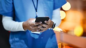 Symbolfoto ÄrztIn oder Gesundheitsfachkraft nutzt Smartphone für Social Media.