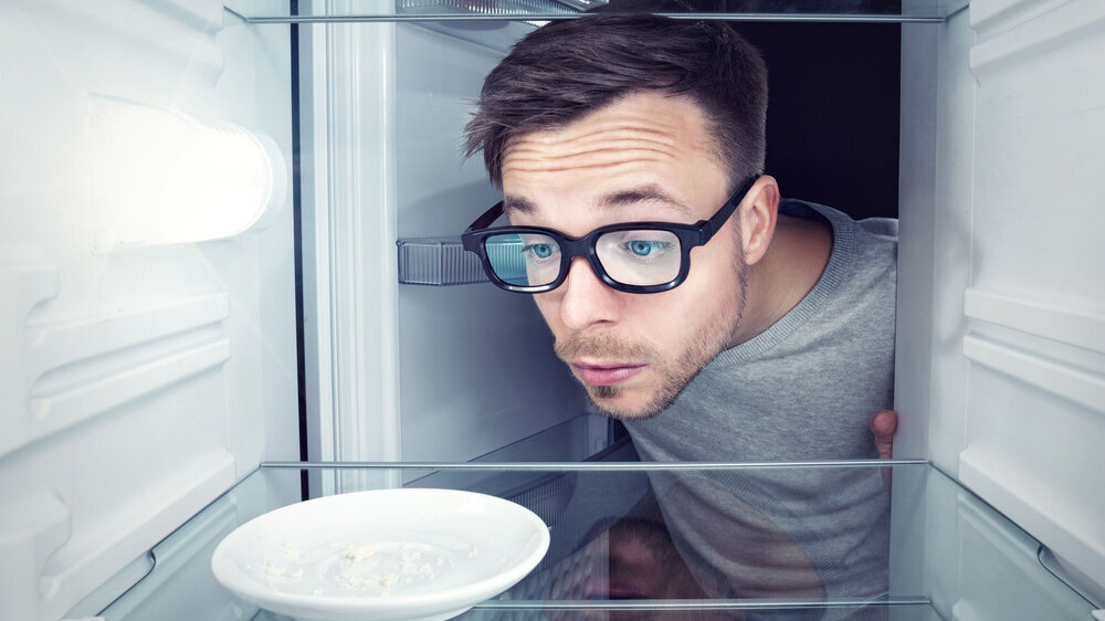 Mann schaut in leeren Kühlschrank