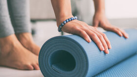 Yoga at home active lifestyle woman rolling exercise mat in living room for morning meditation yoga banner background.