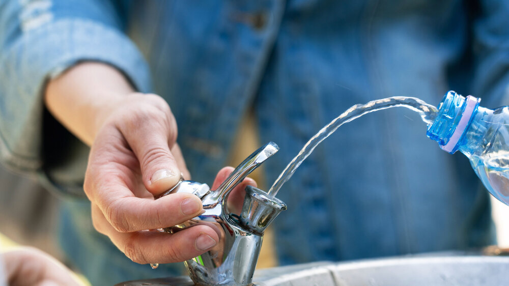 Auffüllen einer Wasserflasche an einem Trinkbrunnen. Auffüllen einer Wasserflasche an einem Trinkbrunnen.