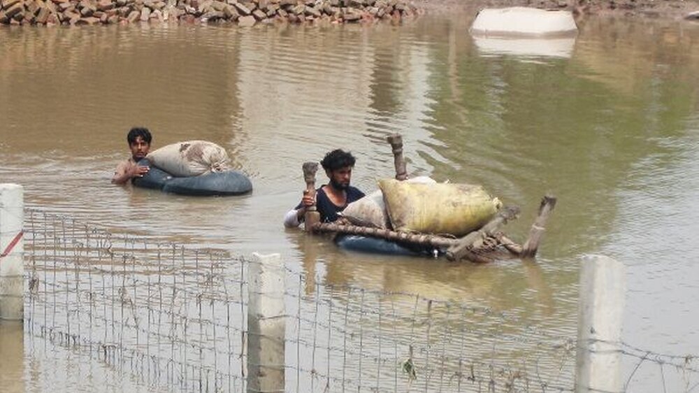 Gefährliche Wassermassen: Zwei junge pakistanische Männer transportieren ihr Hab und Gut auf Plastiktüten durch das Hochwasser.